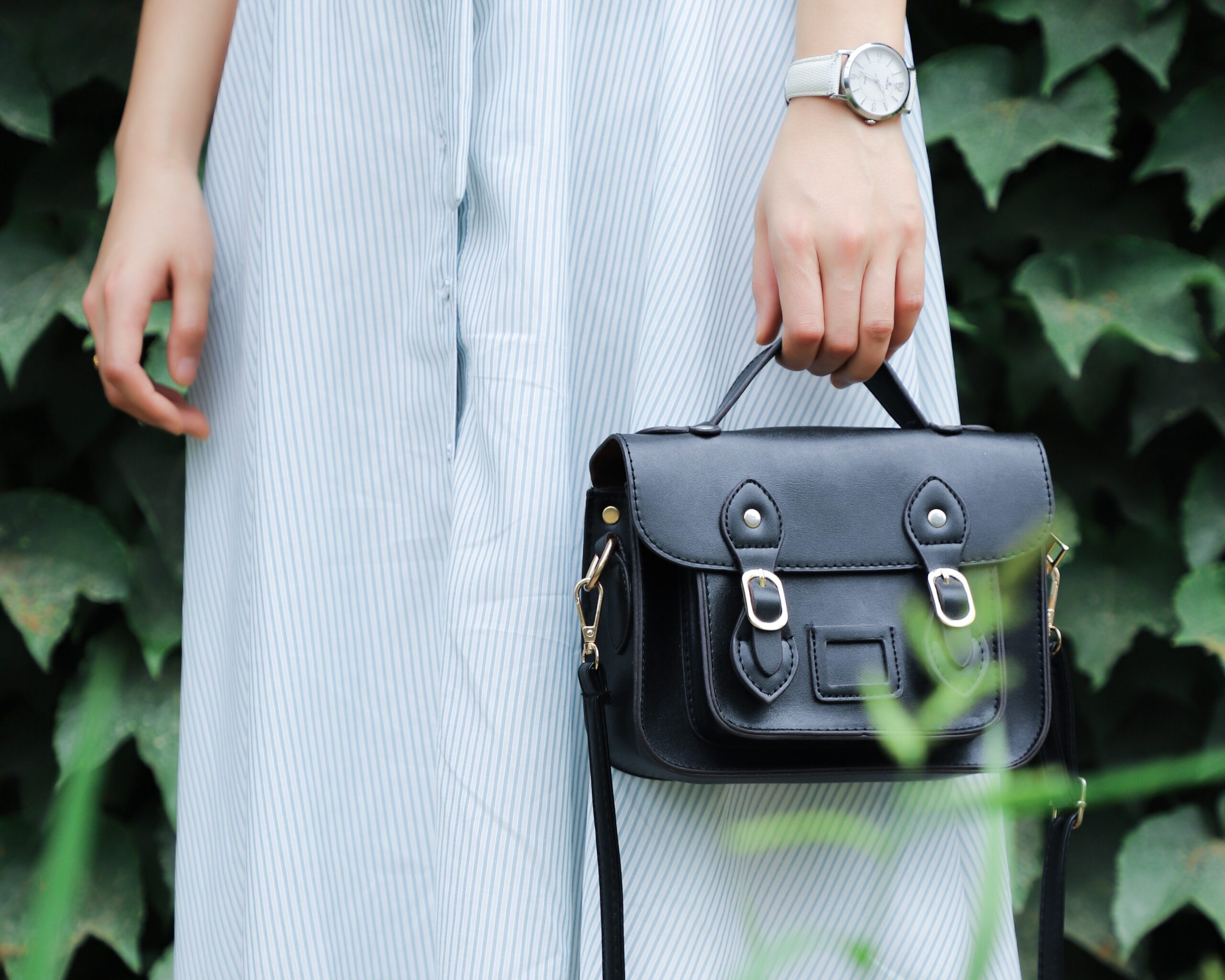 a woman is holding a black purse in her hand.