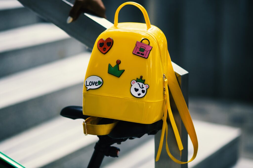 a yellow backpack with stickers on it sitting on a rail.