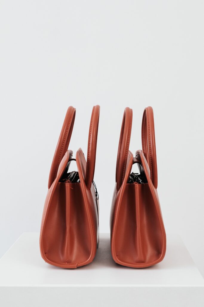 a pair of brown purses sitting on top of a white surface.