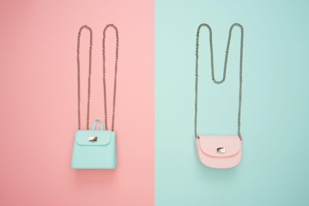 two purses; a pink and a blue purse on a chain.