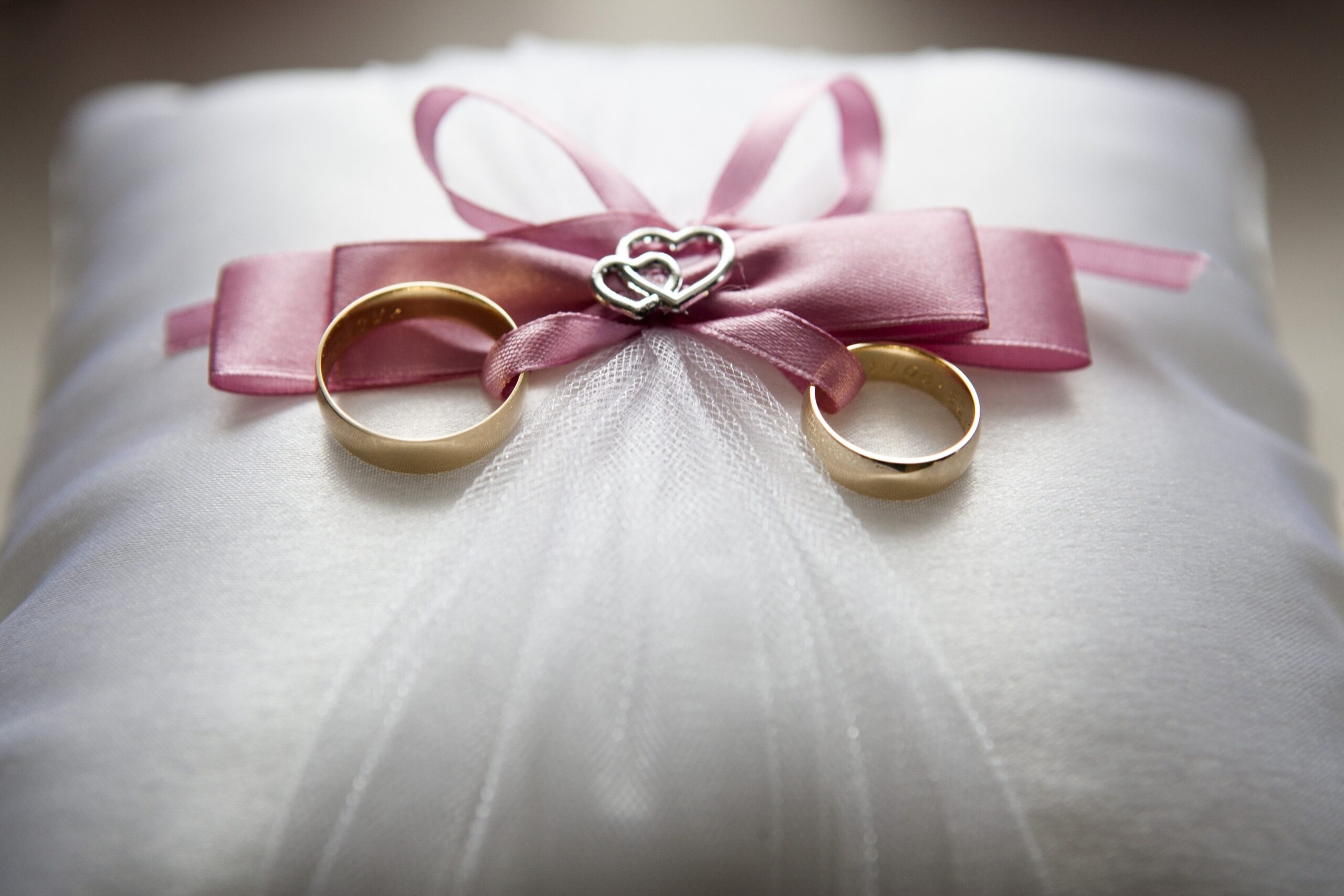 Two gold wedding rings tied together by a silver love symbol