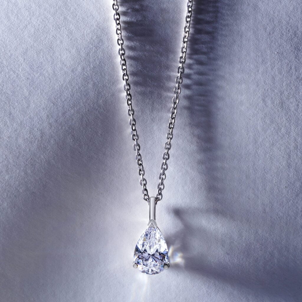 A diamond pendant with numerous tiny diamond pieces hanging on a silver chain