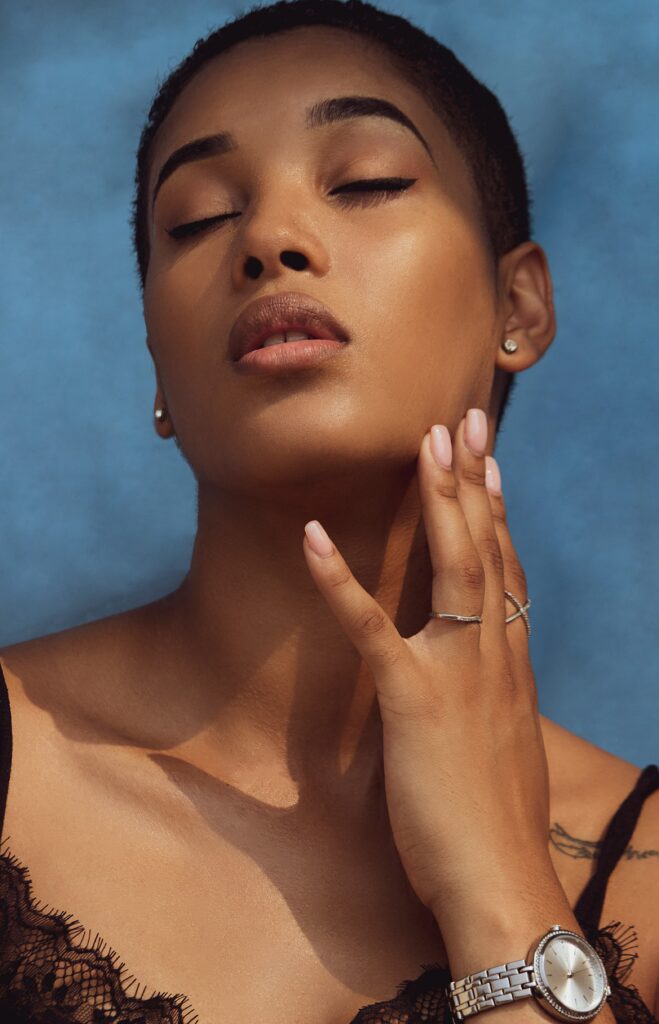 A female model wearing a silver watch, tiny silver earrings and a silver ring