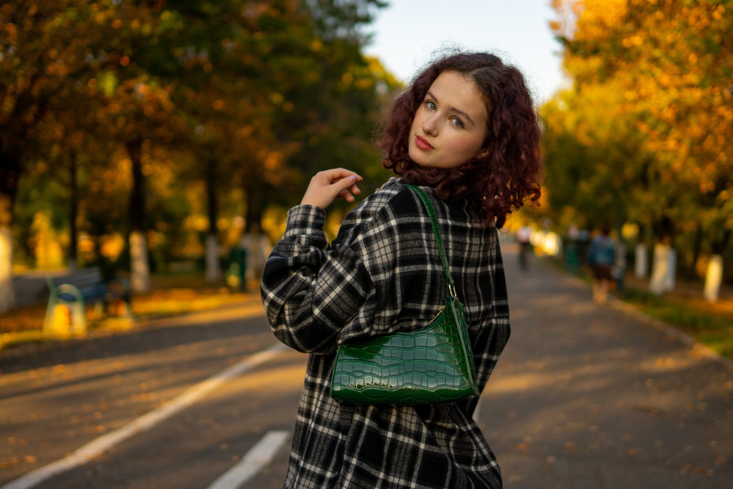 A woman standing on the side of a road holding a green Gift purse from The Supremacyg.